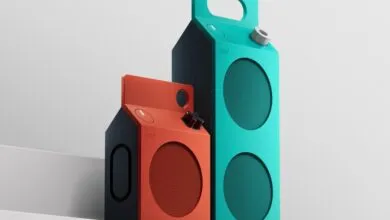 Two vibrant CMF by Nothing portable speakers shaped like milk cartons in orange and turquoise.