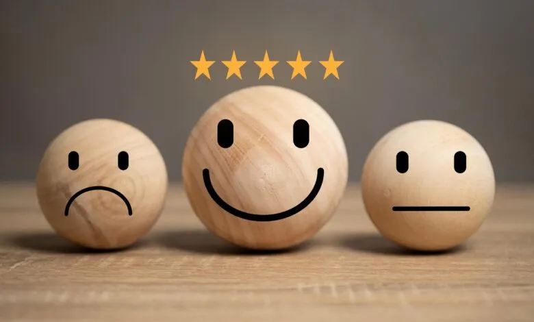 Three wooden spheres with drawn faces showing sad, happy, and neutral expressions, topped with five stars.