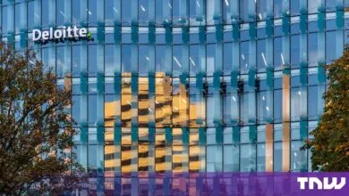 Modern glass facade of a Deloitte office building with reflective windows and corporate signage.