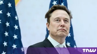 Elon Musk standing in front of United States flags with a thoughtful expression