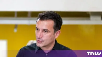 Portrait of Erion Veliaj, Mayor of Tirana, wearing a dark shirt in front of a yellow wall.