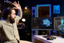 A bearded man reacts with alarm, throwing his hands up while looking at dual computer monitors displaying AI graphics.