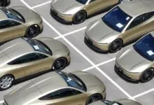 An aerial view of multiple sleek, gold-colored electric cars parked neatly in an outdoor lot.