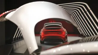 Red Tesla parked inside modern garage framed by open white trunk and aerodynamic curves.