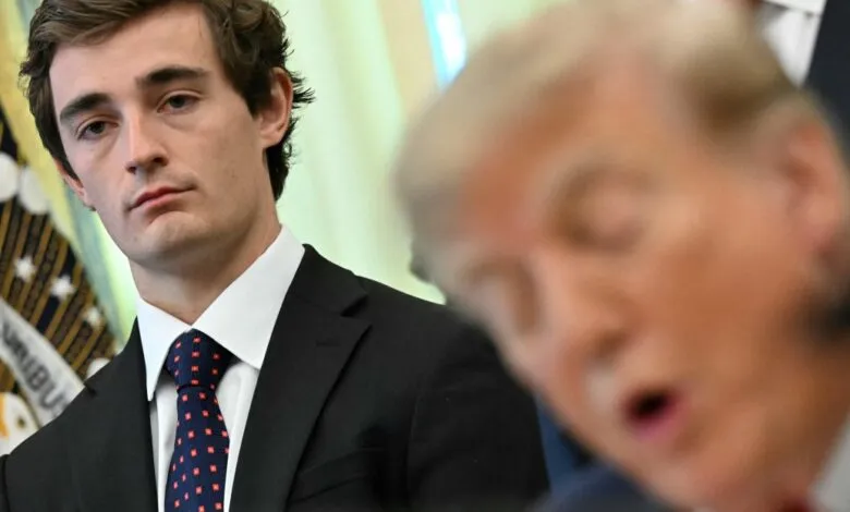 A young man in a suit and tie stands near President Donald Trump