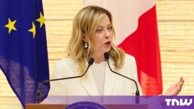 Italian Prime Minister Giorgia Meloni speaking at a podium before EU and Italian flags.