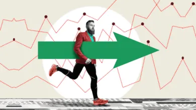 A bearded man in a red blazer runs forward while carrying a large green growth arrow.
