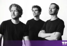 Three male founders wearing black t-shirts pose together against a plain white background.