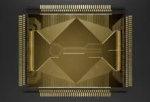Top-down view of a complex golden Helios microchip with intricate circuitry on a dark background.