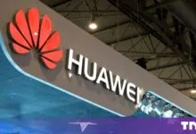 Illuminated Huawei logo displayed on a large exhibition booth structure indoors.