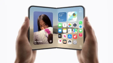 Hands holding a futuristic foldable smartphone with a wide, open touchscreen displaying iOS widgets and apps.
