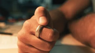 Close-up of a person wearing a sleek smart ring with a glowing notification light on their finger.