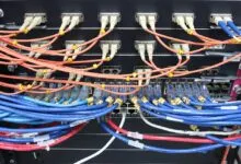 Close-up of network server racks with organized orange, blue, and white fiber optic cables.