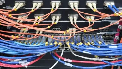 Close-up of network server racks with organized orange, blue, and white fiber optic cables.