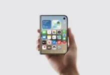 A hand holds a sleek folding smartphone concept displaying a vibrant iOS-style home screen.