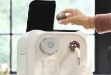 A person placing a K-Cup pod into a modern white Keurig coffee machine
