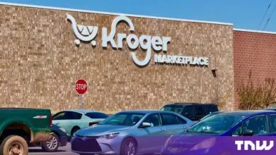 Exterior facade of a Kroger Marketplace store with a large brick wall and parking lot full of cars.