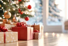 Wrapped Christmas gifts rest on a hardwood floor under a decorated holiday tree with glowing lights.