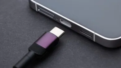 Close-up of a USB-C cable approaching the charging port of a modern smartphone on a dark surface.