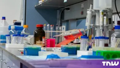 A cluttered laboratory bench with various scientific equipment, test tubes, pipettes, and reagent bottles.