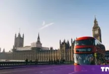A red double-decker bus crossing Westminster Bridge with Big Ben and the Houses of Parliament behind it.