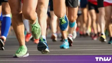 Close-up of diverse marathon runners' legs and colorful running shoes sprinting on a city road.
