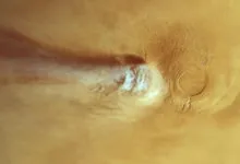 Satellite view of an elongated white cloud streaming from Arsia Mons volcano on Mars
