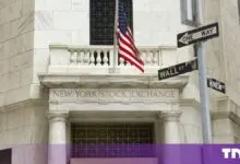 Entrance of the New York Stock Exchange building with American flag and Wall Street street sign