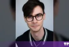 Portrait of Nick Frosst, AI researcher and co-founder of Cohere, wearing glasses and a dark jacket.