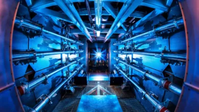 Fisheye view of the NIF laser preamplifier room with blue lights and parallel optical tubes.