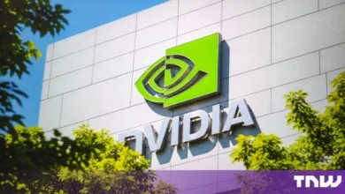 NVIDIA logo mounted on the tiled exterior wall of a corporate building with lush green trees framing it