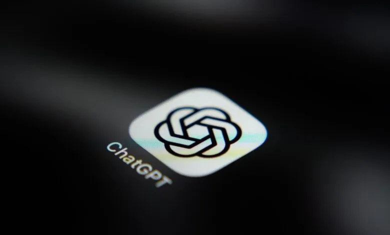 Close-up of the ChatGPT app icon glowing on a dark smartphone screen in low light.
