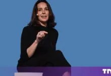 Mira Murati speaking on stage against a solid blue background