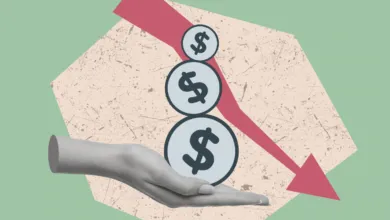 A grayscale hand supports three dollar sign coins beneath a downward trending red arrow.