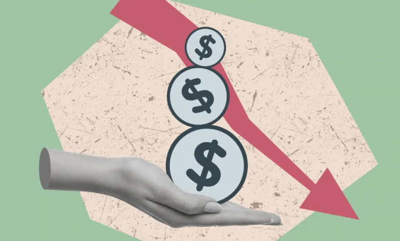 A grayscale hand supports three dollar sign coins beneath a downward trending red arrow.