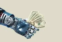 A metallic robotic arm holding a fan of United States dollar bills against a plain background.