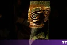 Sanxingdui bronze head with gold mask displayed against a dark background