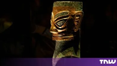 Sanxingdui bronze head with gold mask displayed against a dark background