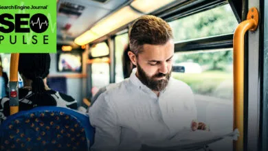 A bearded man reading a document on a crowded public bus during his commute.