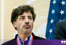 Google co-founder Sergey Brin wearing a medal with an American flag in the background.