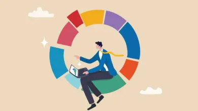 A businessman sits inside a colorful segmented pie chart while using a laptop.