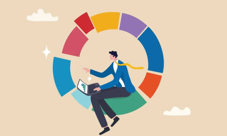 A businessman sits inside a colorful segmented pie chart while using a laptop.