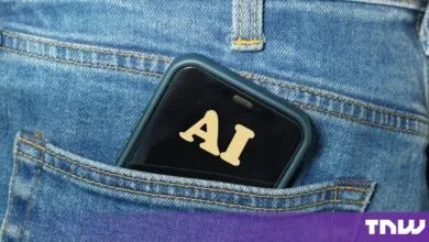 A smartphone displaying the letters AI on screen sits in the back pocket of blue jeans.
