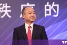 SoftBank CEO Masayoshi Son speaking on a stage with a purple background.