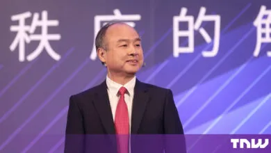 SoftBank CEO Masayoshi Son speaking on a stage with a purple background.