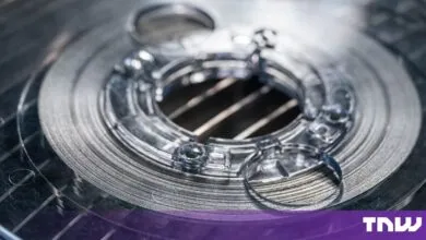 Close-up view of a metallic spool of superconducting tape with a complex center hub.