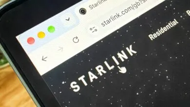 Close-up of a laptop screen showing the Starlink website homepage with white logo and starry background.