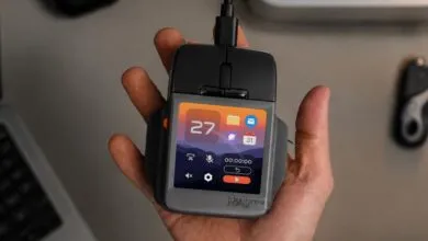 A person holding an unconventional computer mouse featuring a built-in color display screen.