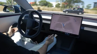 Driver with hands off the steering wheel inside a Tesla using Full Self-Driving technology.