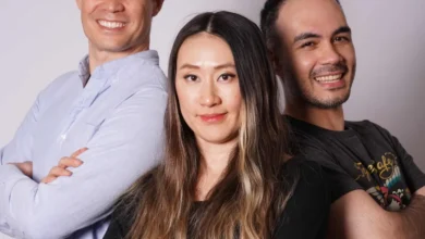 Three confident professionals standing with arms crossed against a plain grey backdrop.